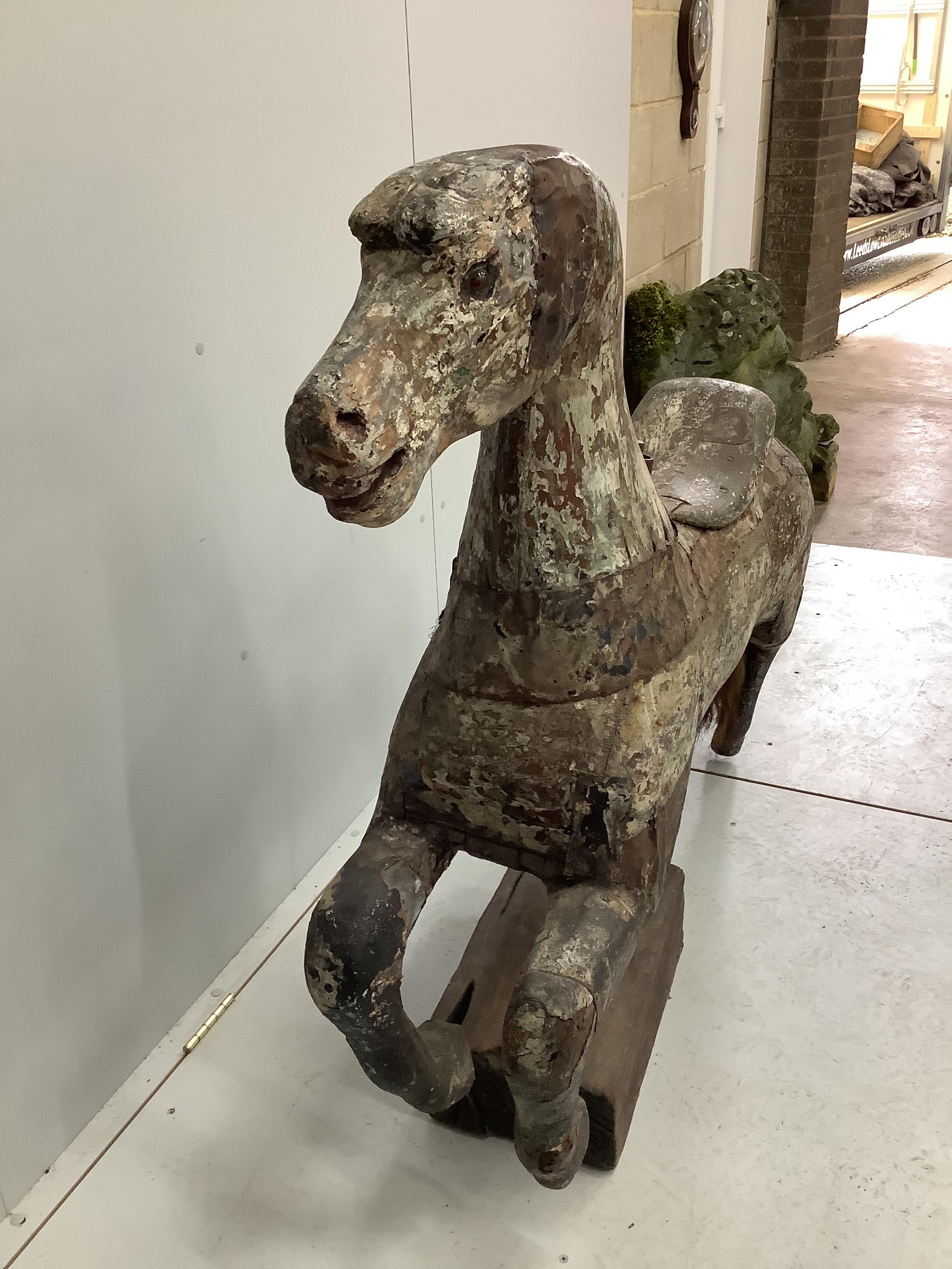 A vintage metal bound carved wood carousel fairground horse with traces of original paint, length 128cm, height 118cm